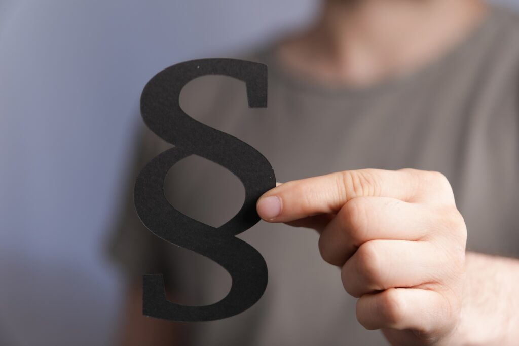 Male hand holding a black paragraph law sign
